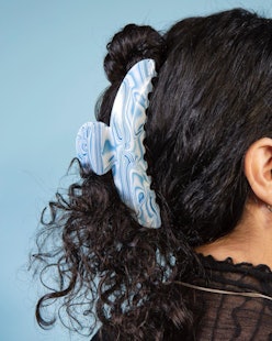 Woman with her curly hair up in a clue marbled Chunks claw clip