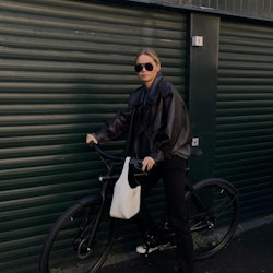 Claire Rose riding a bike with a white Prada handbag
