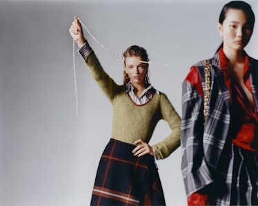 Two models wearing Salvatore Ferragamo knit sweater, shirt, skirt; Hannah Jewett earrings. Marni jac...