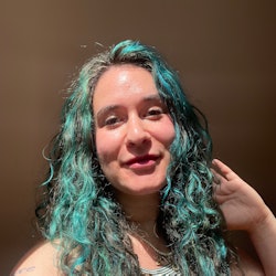 woman with curly blue hair and glowing skin