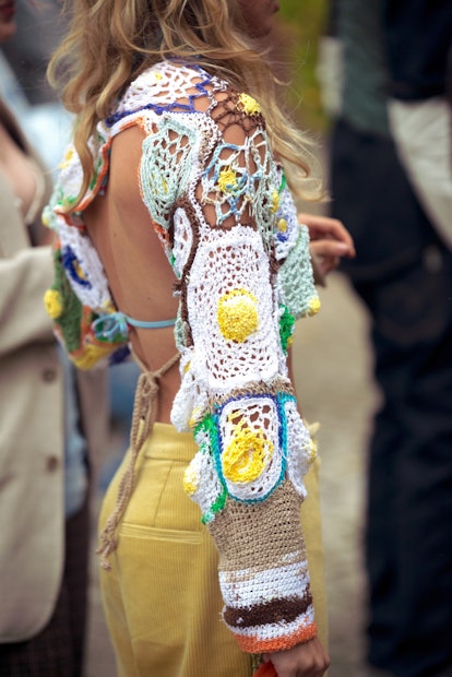 A woman wearing colorful crochet top and yellow pants.