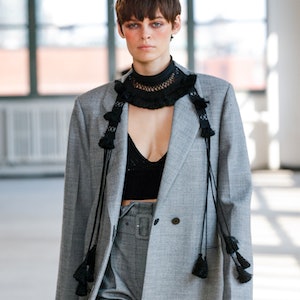 A model wearing a grey suit an dblack crochet top on the Altuzarra Spring/Summer runway