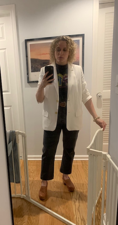 A woman in a white blazer and black pants, and a graphic tee.