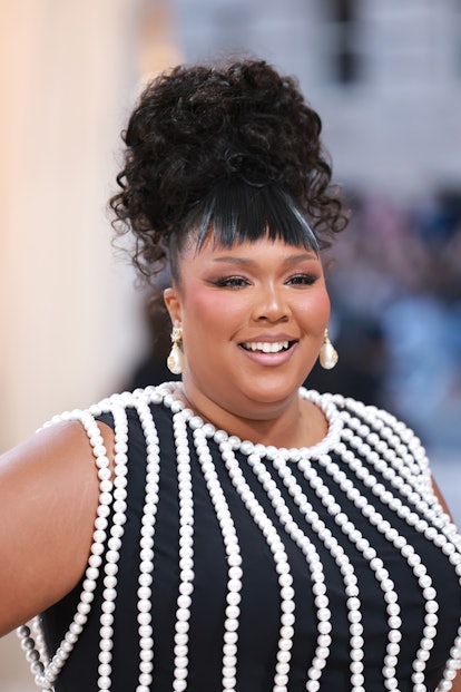 lizzo at the 2023 met gala wearing a curly updo and choppy bangs 