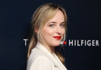 Dakota Johnson with blonde hair and bare forehead and red lipstick at the arrives at the Tommy Hilfi...